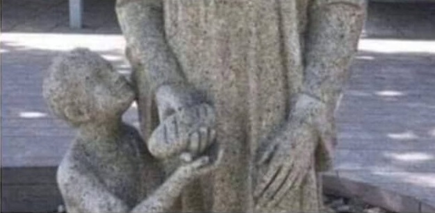 Catholic Church with child abuse in statues: A
                  "saint" holds a loaf of bread positioned
                  where the doodle is
